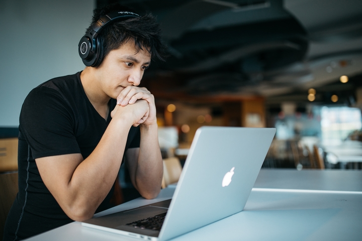 Photo by Wes Hicks on Unsplash Man wearing headphones while sitting on chair in front of MacBook